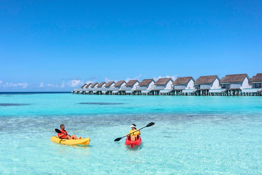 Kayak along Maldives island shores in clear lagoon waters