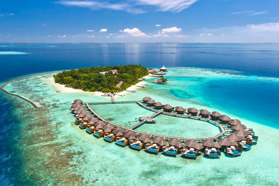 Tropical Maldives resort island surrounded by coral reef and lagoon